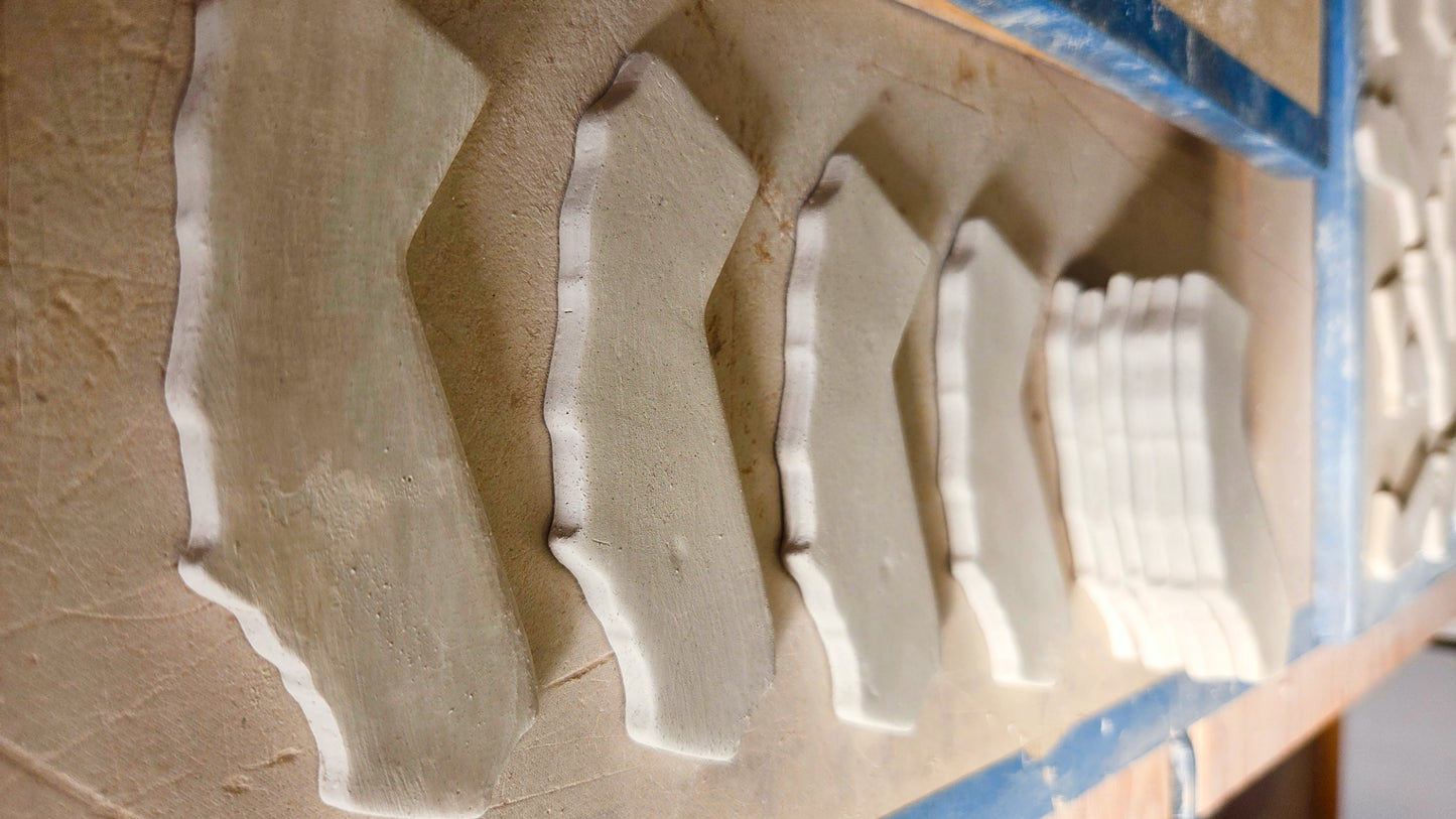Raw unglazed ceramic California state shape magnets drying in workshop before firing and personalization into custom souvenir magnets