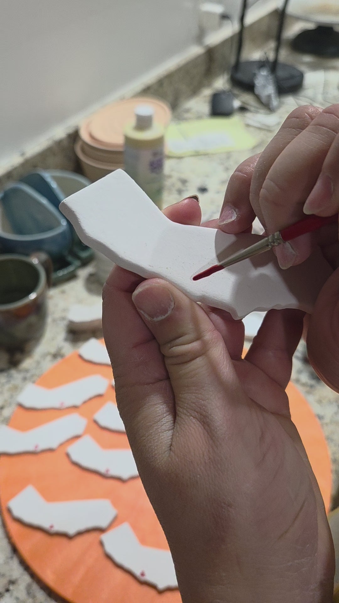 California white ceramic magnet with red heart being hand applied.